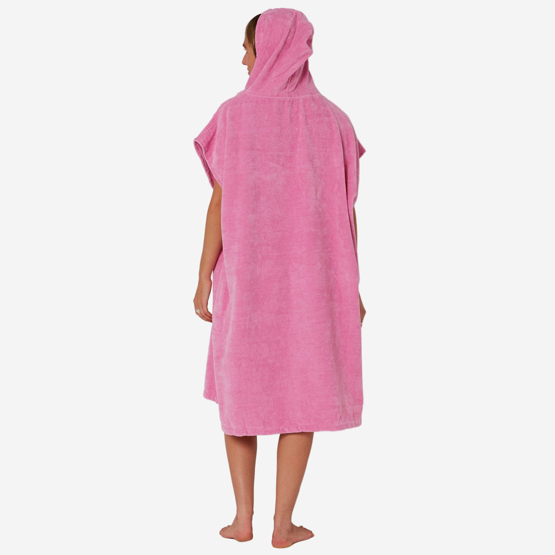 Person wearing a pink hooded towel on a plain background