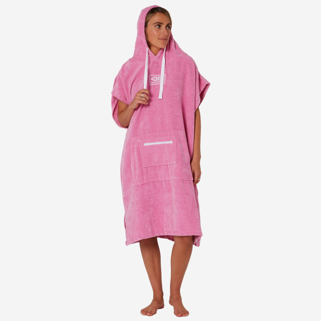 Person wearing a pink hooded towel on a plain background