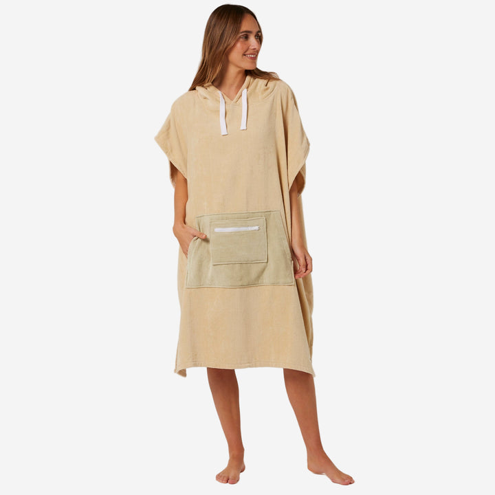 Woman wearing a beige towel dress with a pocket on a plain background