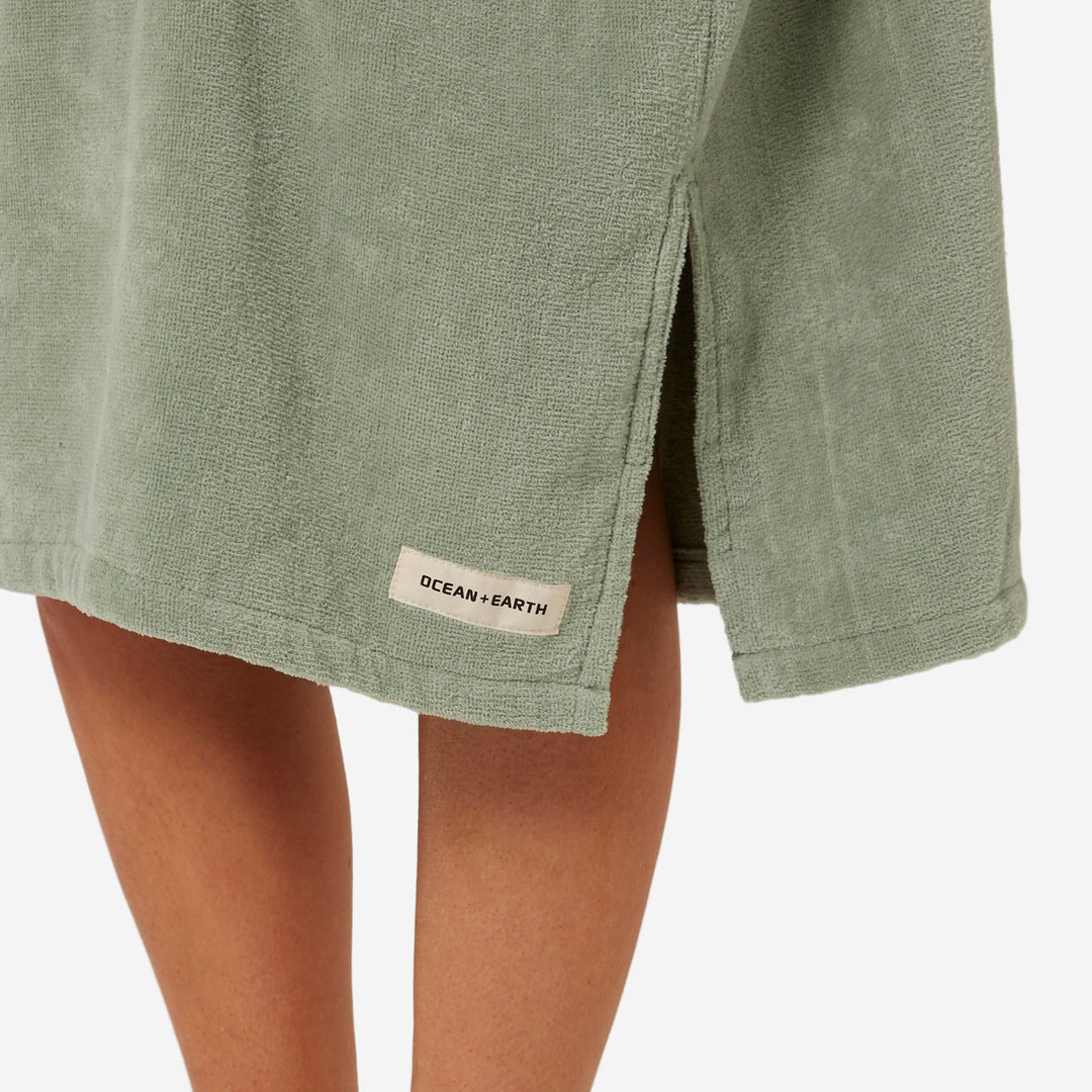 Green towel with 'Ocean & Earth' label draped over a person on a neutral background