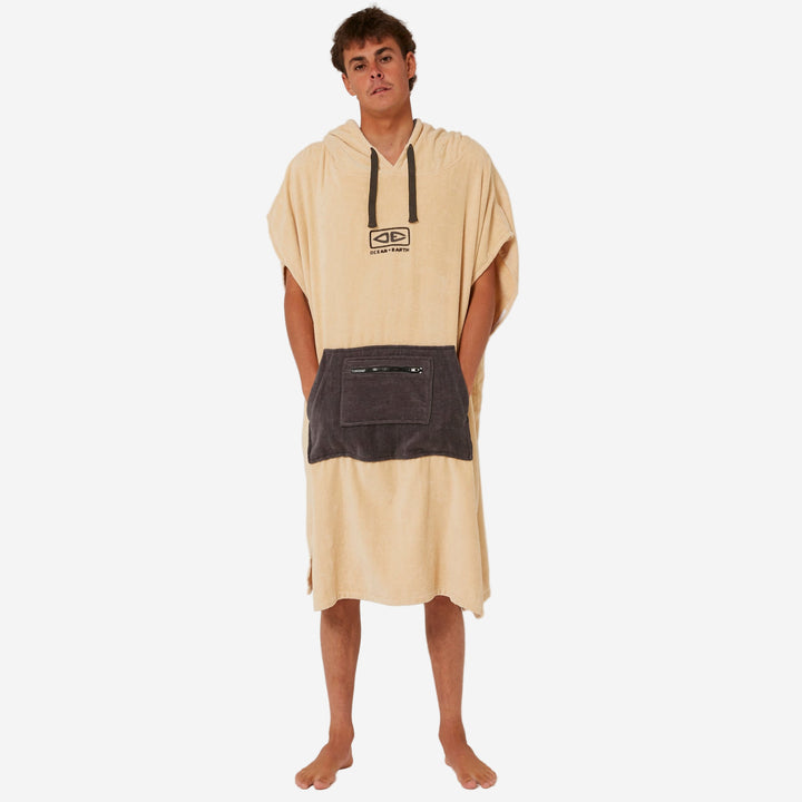 Person wearing a beige and black poncho with a logo on a white background